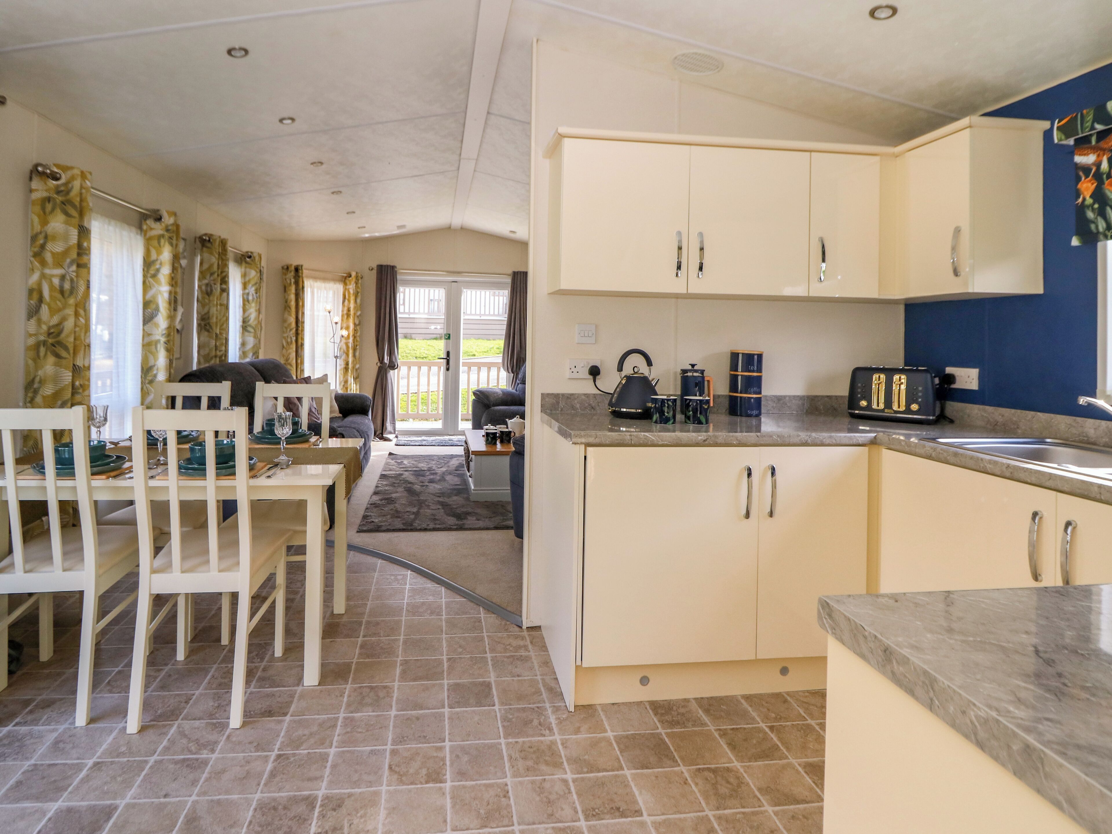 A compact kitchen with basic amenities, a dining area with a table and chairs, and a view of the outdoors through a door.