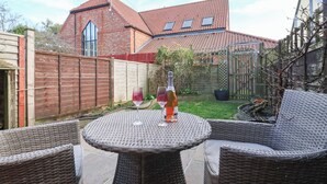 A patio with wicker furniture and a bottle of wine.