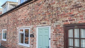 A brick building with a green door and a number 31 sign.