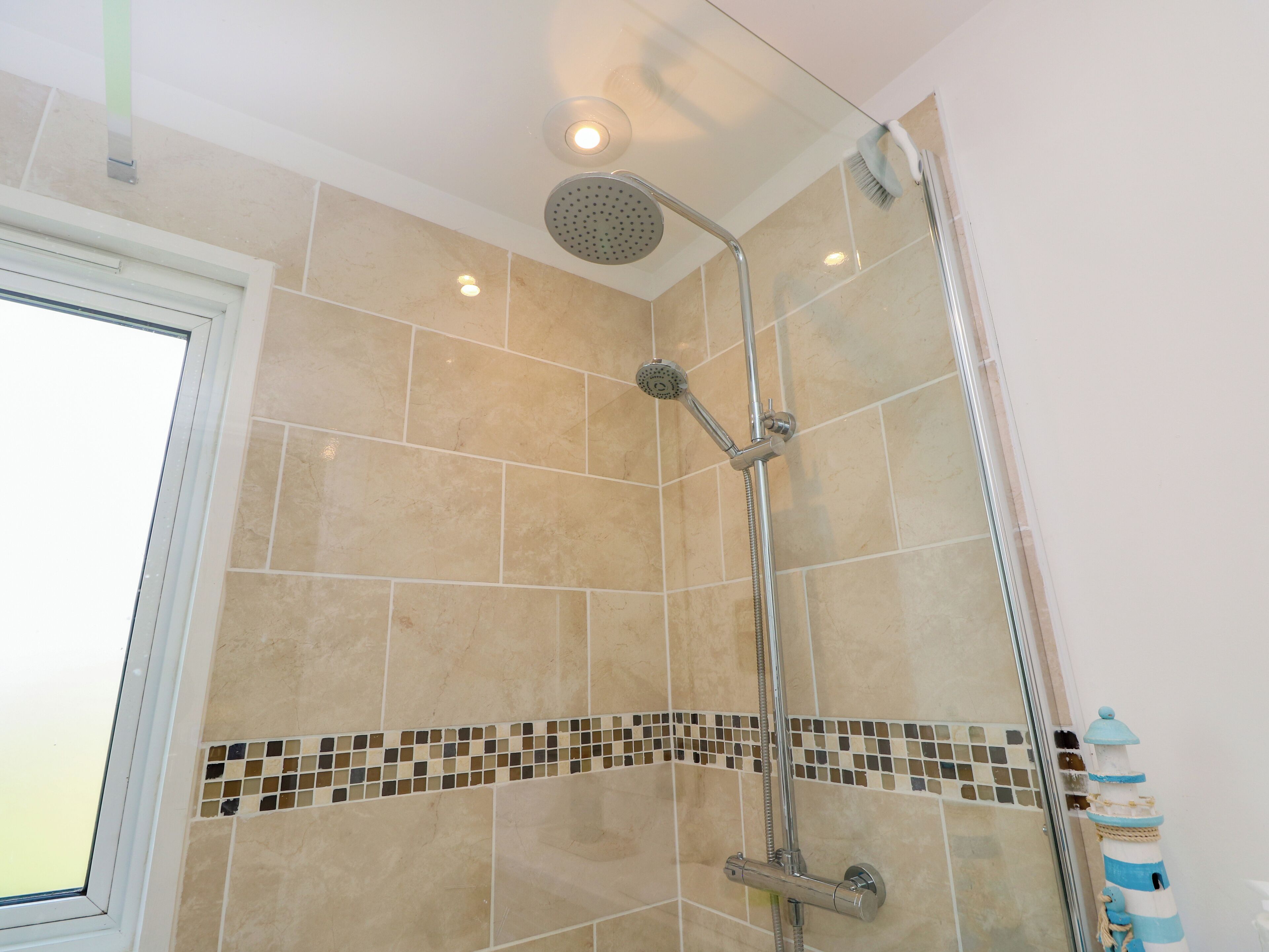 Eine Dusche mit Handbrause, Regendusche und Reinigungsbürste.