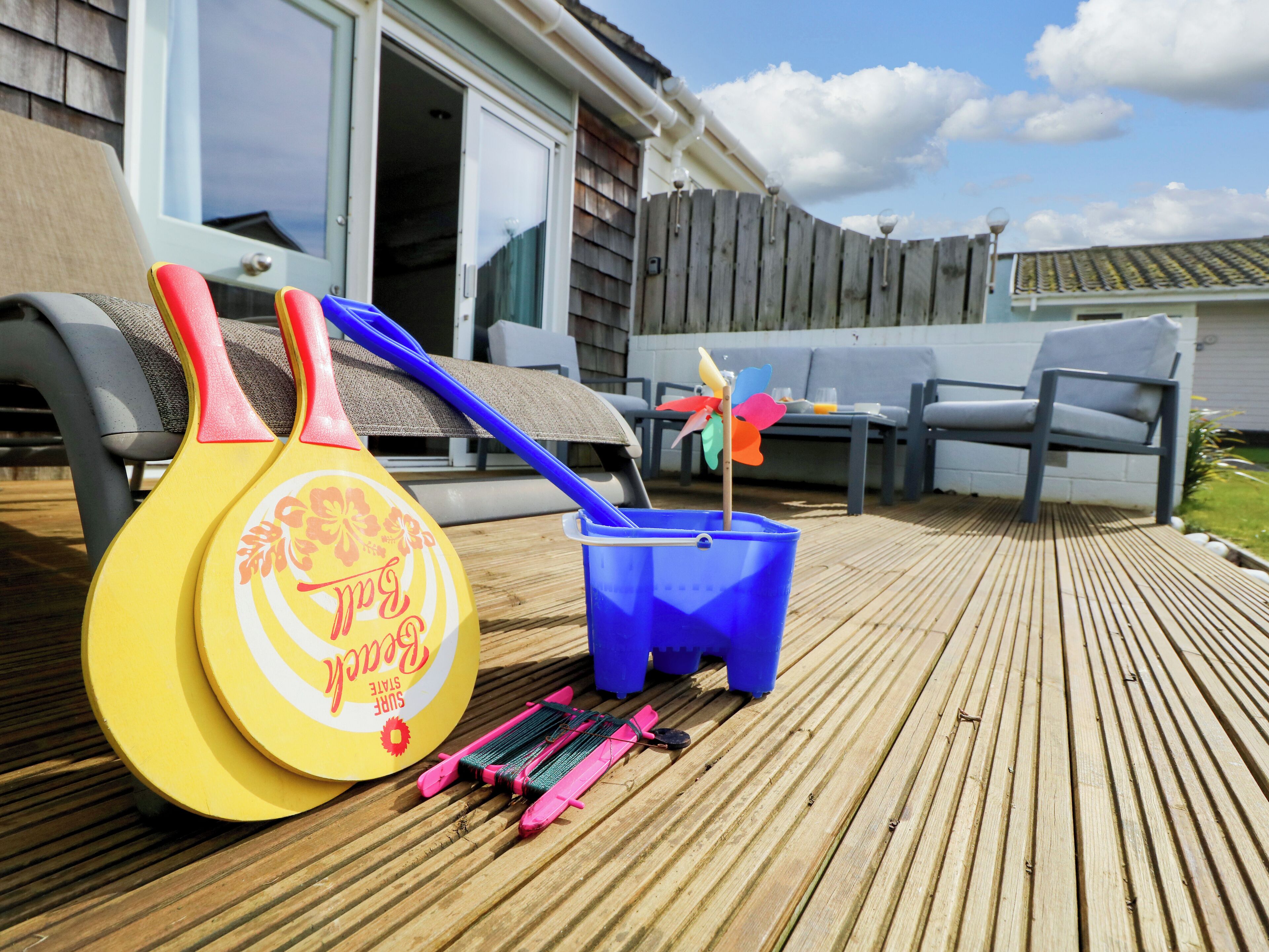 A wooden deck with a badminton net, a blue bucket, and a pinwheel.
