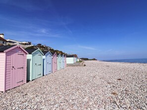 A row of colorful beach huts along a pebble beach with a clear sky.