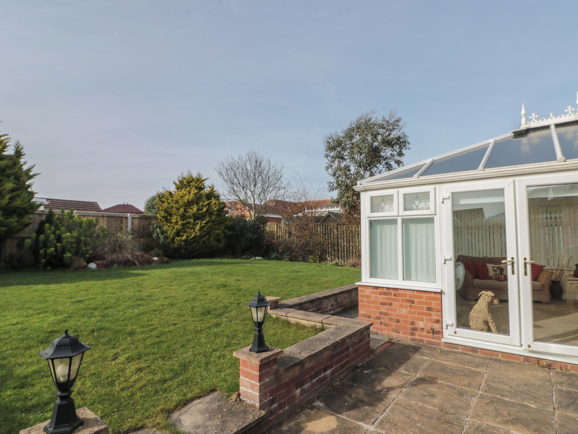 A conservatory with a glass door, a brick wall, and a lawn.