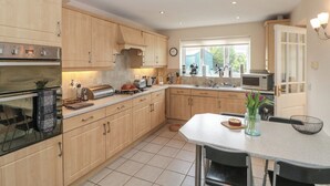 A modern kitchen with wooden cabinets, stainless steel appliances, and a dining area with a table and chairs. - Bray Nook, 7 Craikewells (Bridlington)