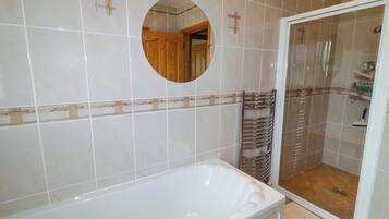 Un baño moderno con una bañera blanca, ducha con cerramiento de vidrio y puerta de madera.