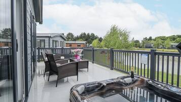 Un balcon agrémenté de meubles en osier, un jacuzzi et une vue sur un lac et des maisons.