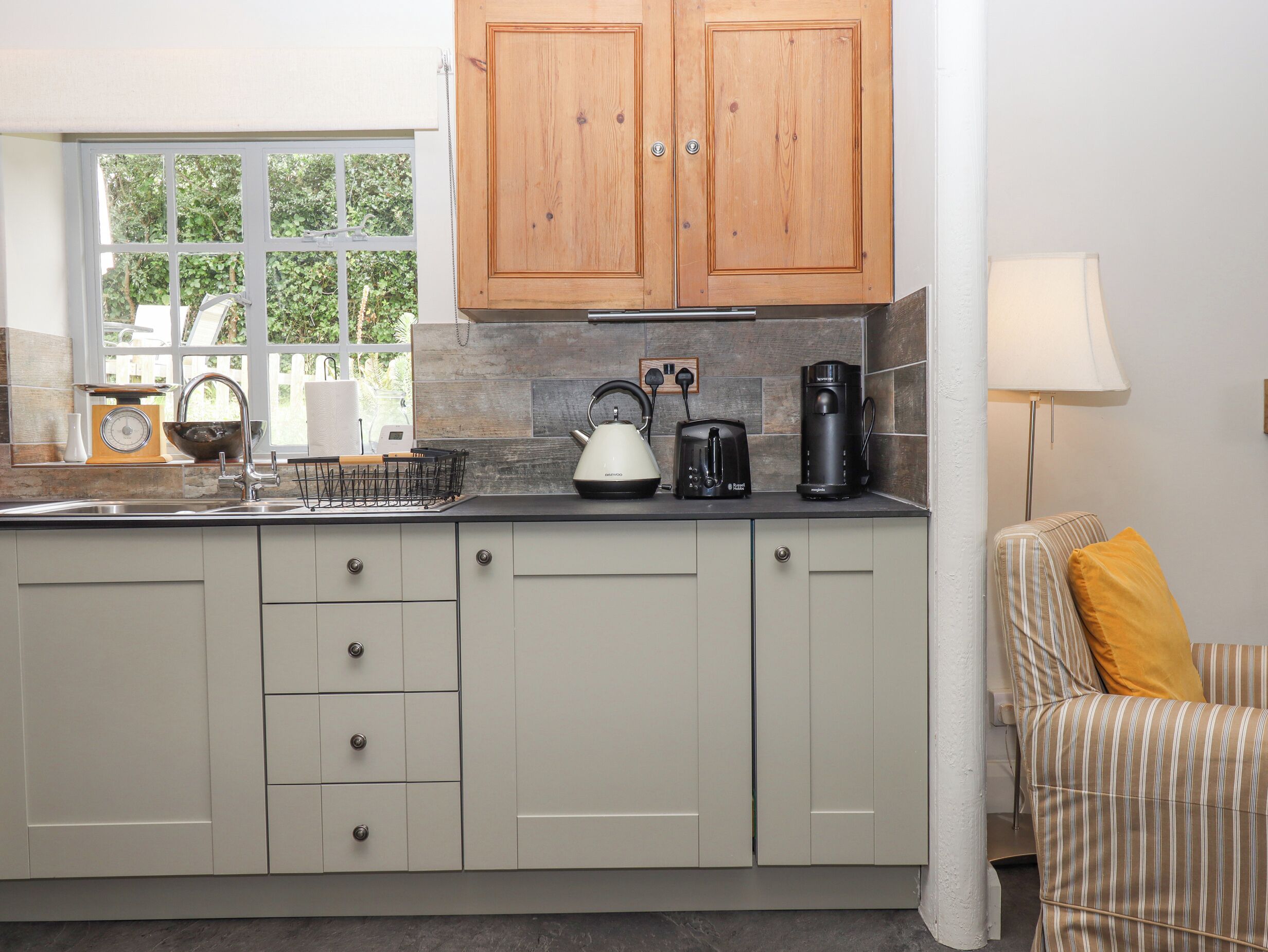 A kitchen with wooden cabinets, a kettle, a toaster, and a coffee maker on the counter.