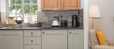 A kitchen with wooden cabinets, a kettle, a toaster, and a coffee maker on the counter.