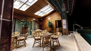 An indoor seating area with tables and chairs, a pool, and a skylight. - Timberwick Green (Wooler)