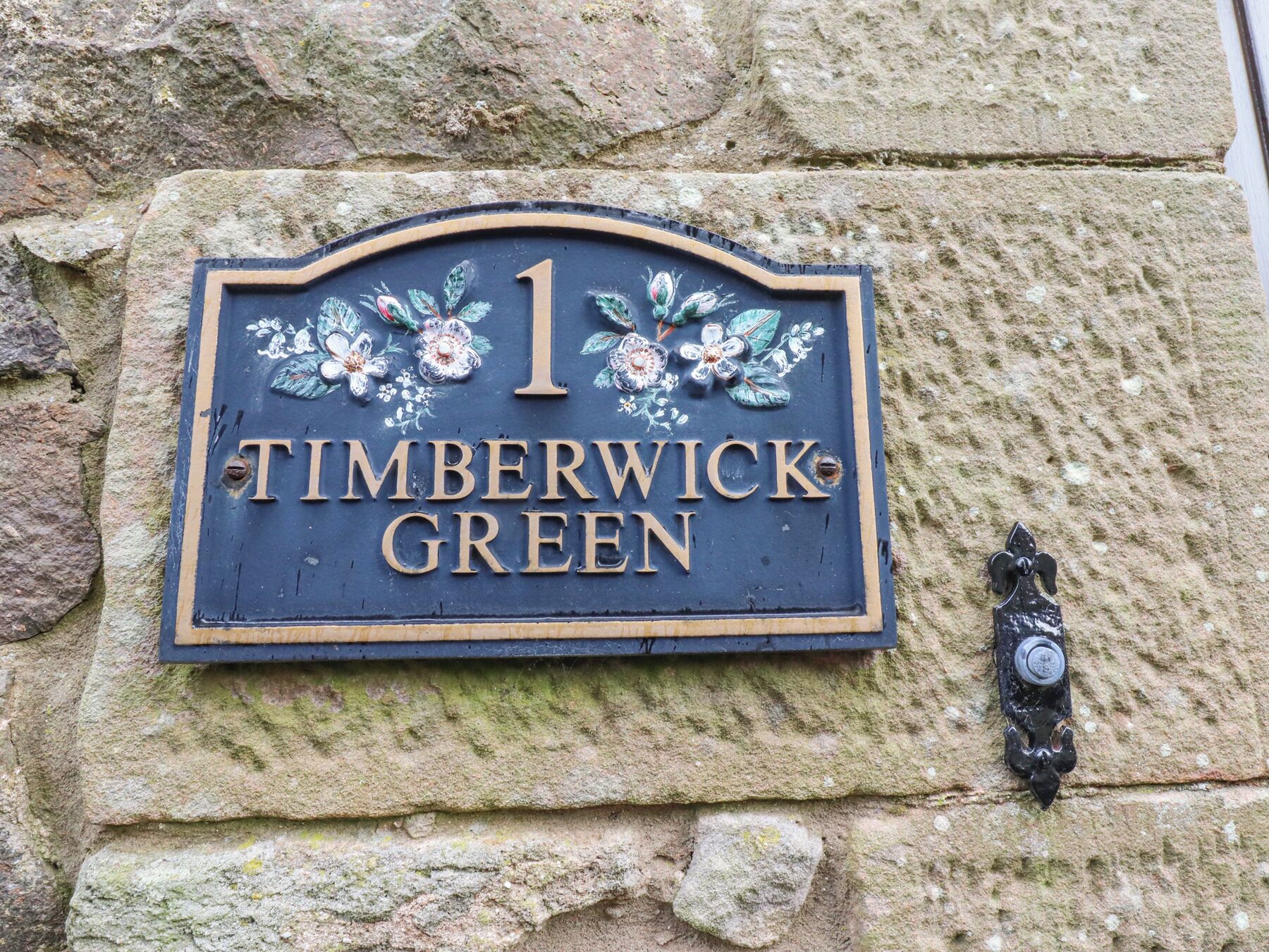A house number sign with floral decorations and the text "1 TIMBERWICK GREEN".