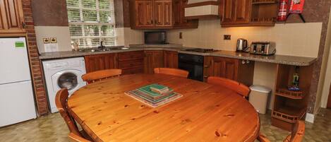 A kitchen with wooden cabinets, a round wooden table, and a built-in oven.