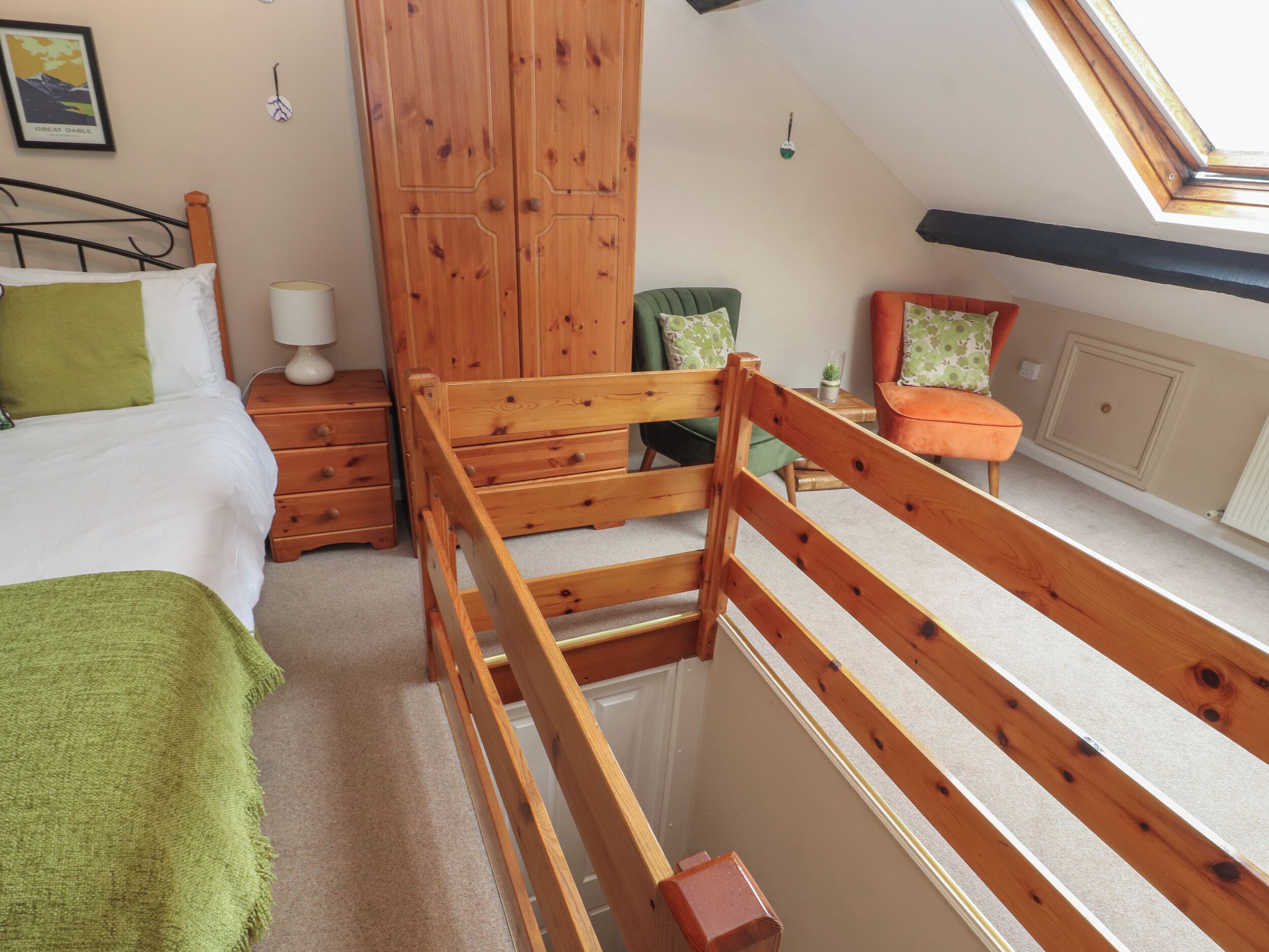 A bedroom with a loft bed, wooden wardrobe, and a small table with a lamp.