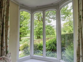Quarto de canto com três janelas em sacada com vista para um jardim.