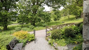 A pathway leading through a park with trees, a bench, and a stone wall. - Hollens Cottage (Ambleside)