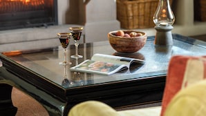 Une table avec un plateau en verre, un magazine, un saladier de fruits et deux verres à vin.