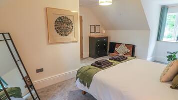A bedroom with a bed, a dresser, a mirror, a framed artwork, and a window with curtains.