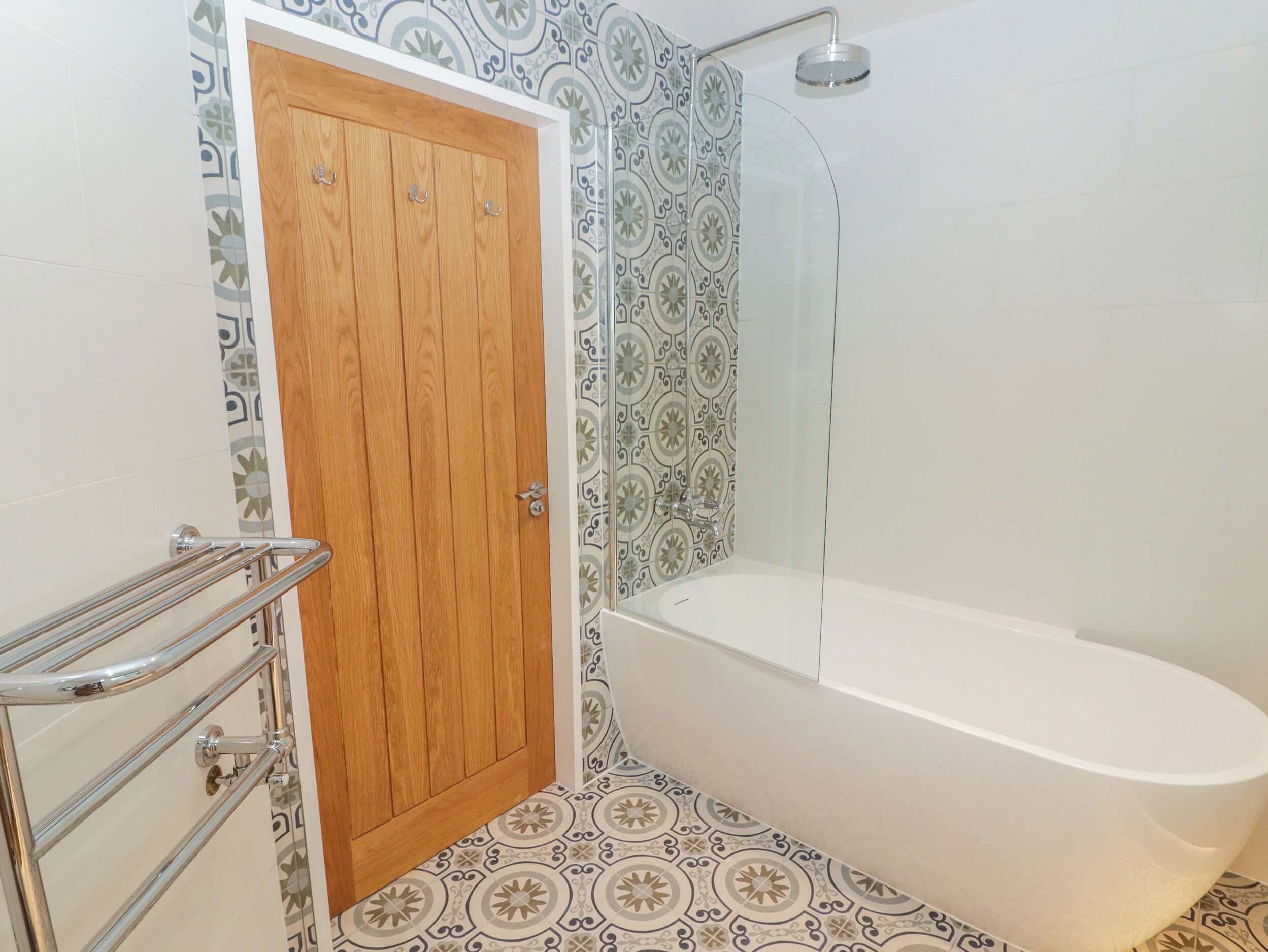 Ein Badezimmer mit Holztür, Duschkabine aus Glas und einer weißen Badewanne.