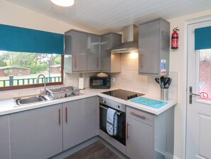 A compact kitchen with grey cabinets, a built-in oven, a microwave, and a gas stove. - Ramson (Saltburn-by-the-Sea)