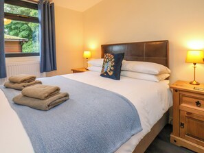 A neatly made bed with a blue blanket, a decorative pillow, and two bedside lamps. - Ramson (Saltburn-by-the-Sea)