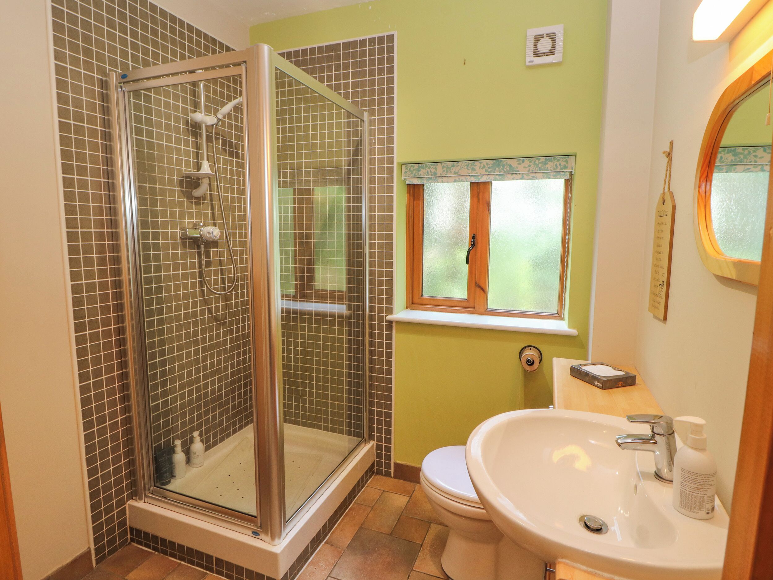 A bathroom with a glass-enclosed shower, a toilet, and a sink with a mirror.