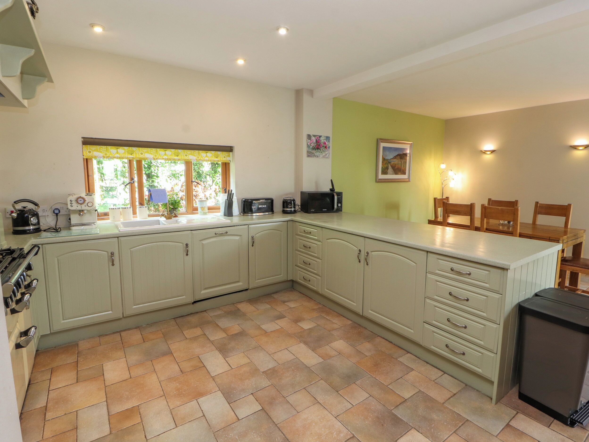 A kitchen with a herringbone tile floor, a microwave, a toaster, and a sink.