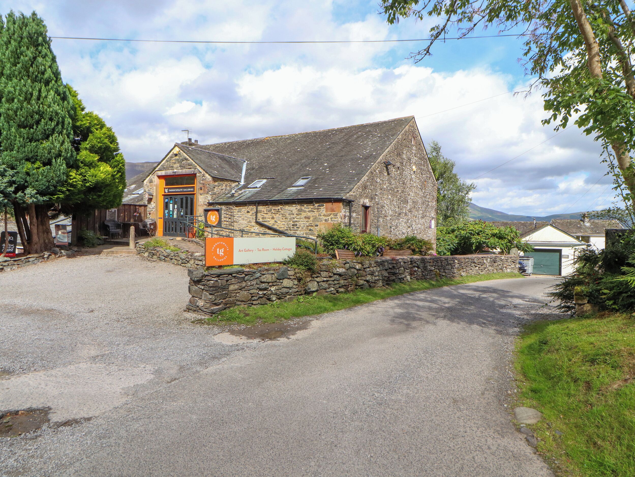 A stone building with a sign indicating it houses an art gallery, tea room, and holiday cottage.