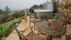 A patio with outdoor furniture, a hot tub, and a view of the countryside. - Quarry House (Montgomery)