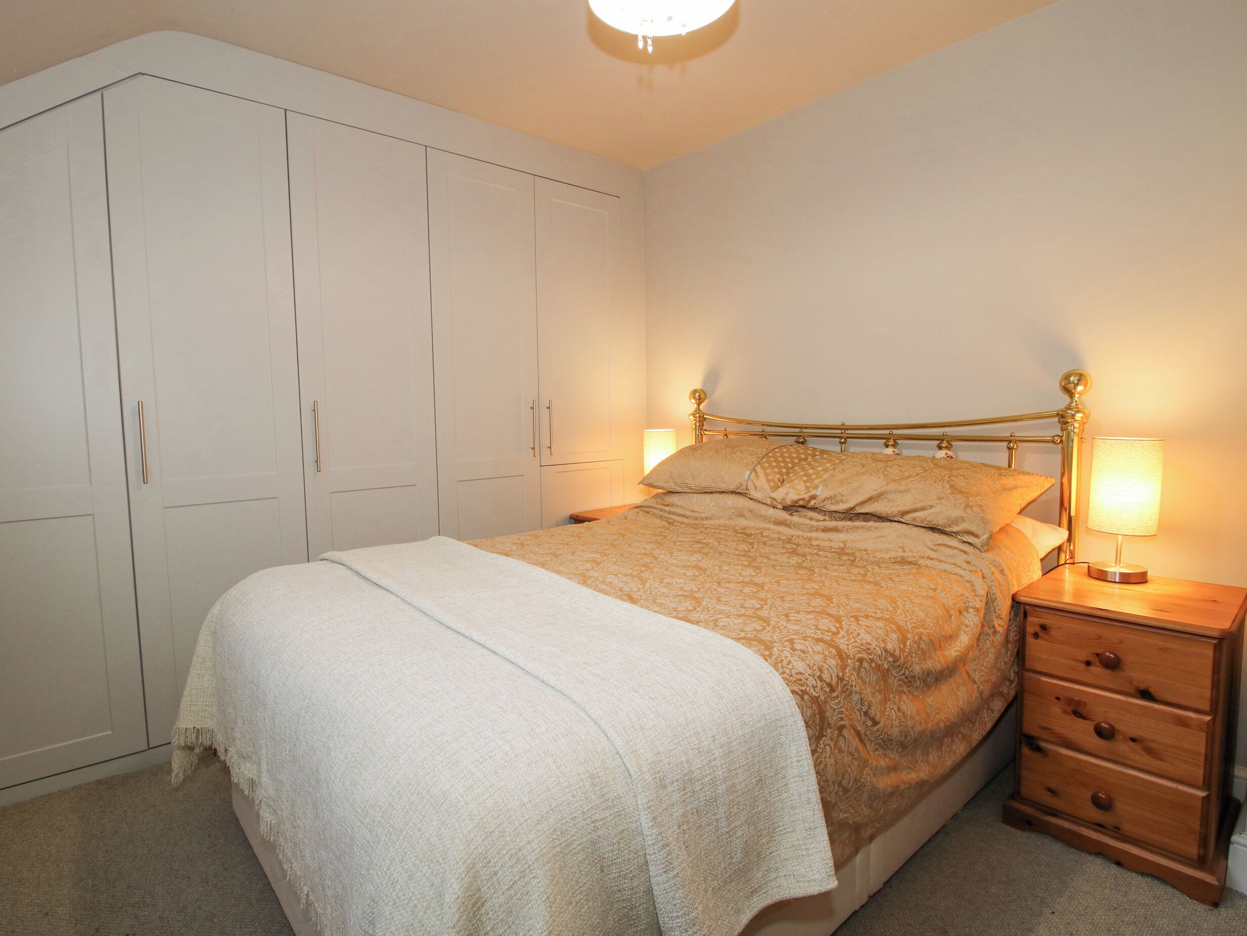 Une chambre à coucher avec un lit, une table de chevet, une lampe et une armoire.