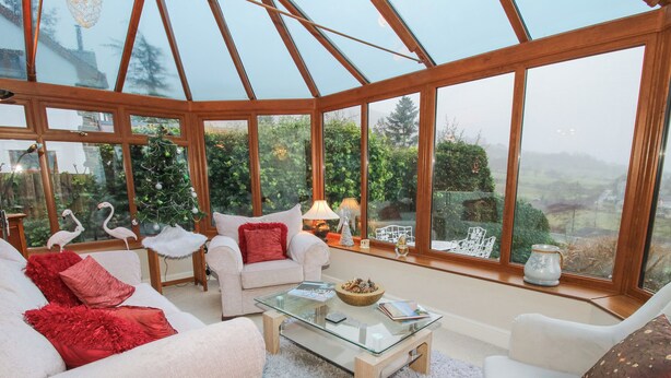 A conservatory with a glass ceiling, white furniture, and a Christmas tree. - Quarry House (Montgomery)