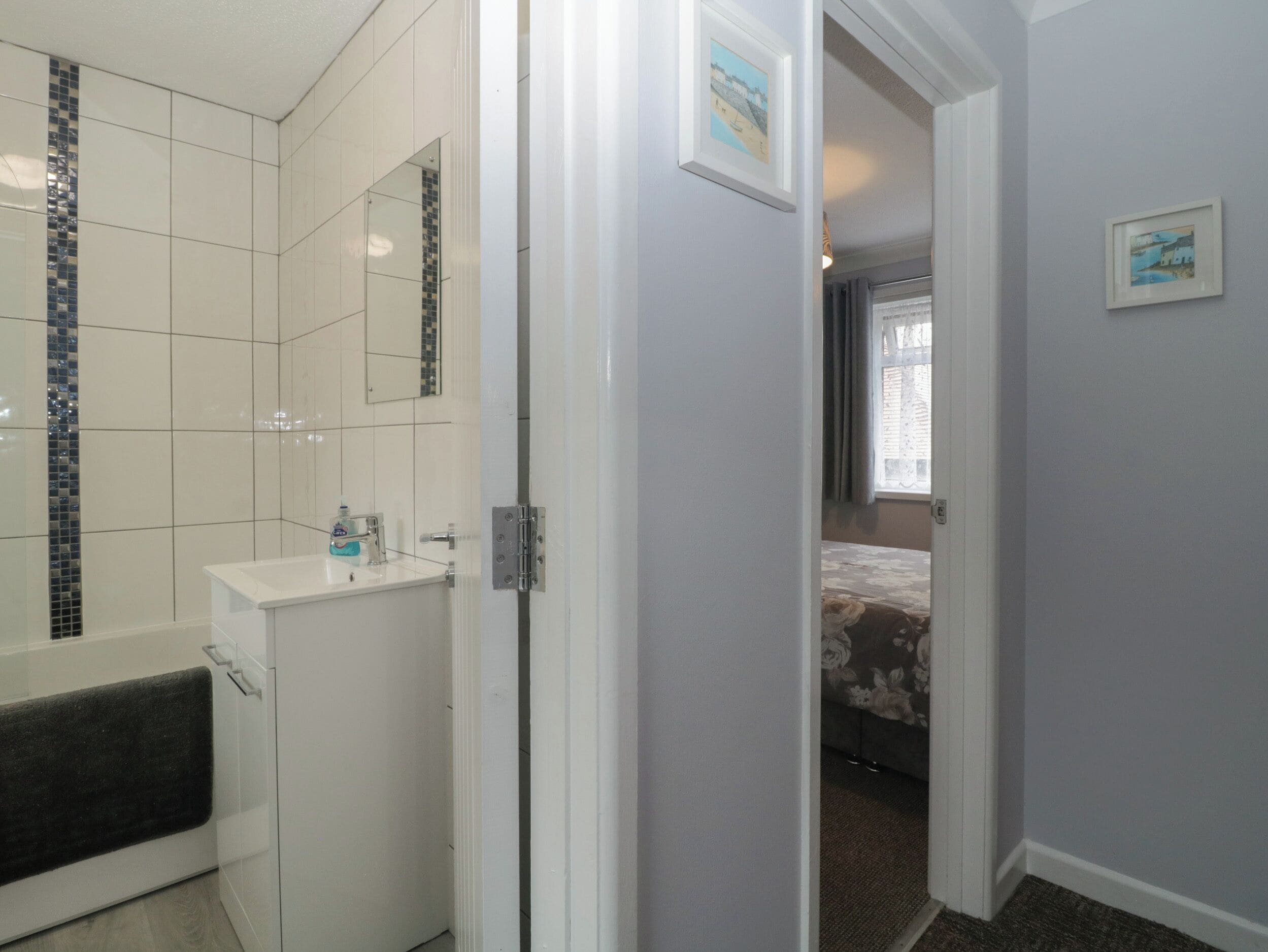 A bathroom with a white sink, mirror, and tiled walls.