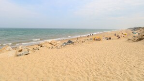 A wide sandy beach with a clear sky, rocky outcrops, and people relaxing. - Chalet 469 (Great Yarmouth)