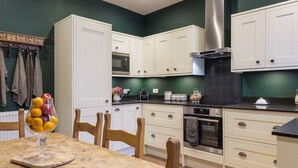 Eine moderne Küche mit weißen Schränken, einer Edelstahl-Dunstabzugshaube und einem Holztisch mit Stühlen.