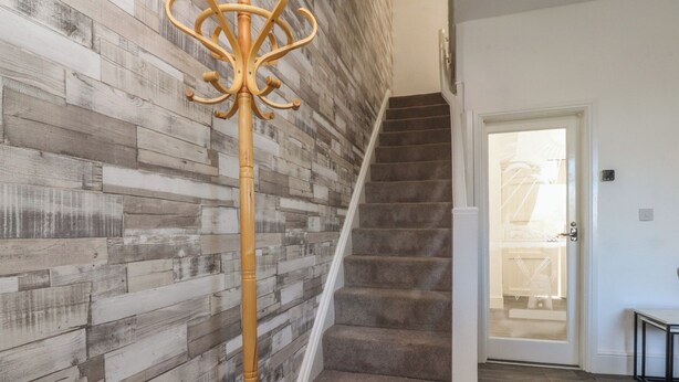 A staircase with a wooden floor and a wall with a wood plank pattern. - Harbour Mews (Lytham St. Anne's)