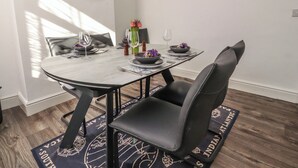 A dining area with a round table, black chairs, and a wooden floor. - Harbour Mews (Lytham St. Anne's)