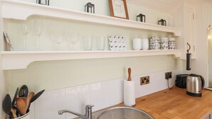 A kitchen with white shelves, a sink, and a kettle. - Woodlands Retreat Shepherd's Hut (Woodbridge)