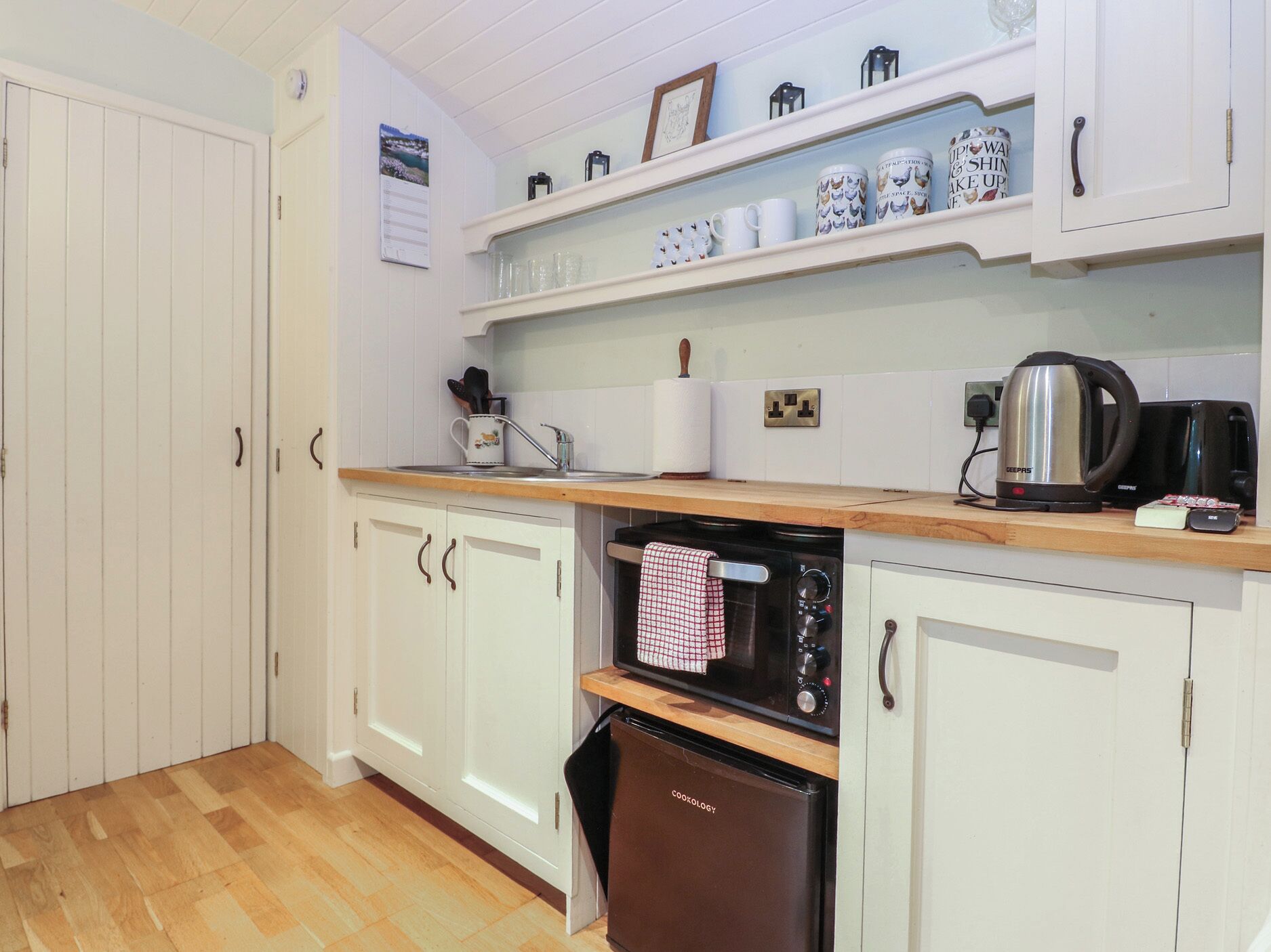 A kitchen with white cabinets, a wooden countertop, a black oven, and a coffee maker.