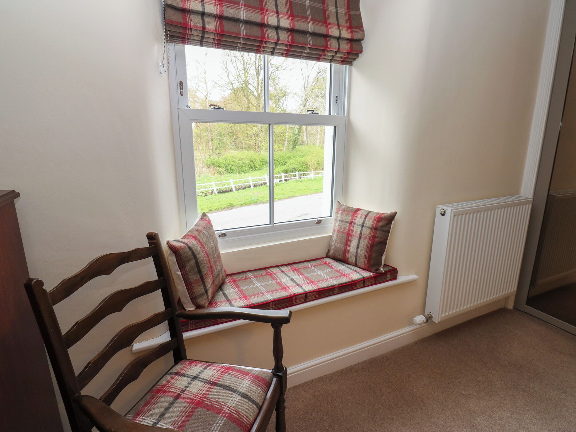 A room with a window seat, a radiator, and a chair.