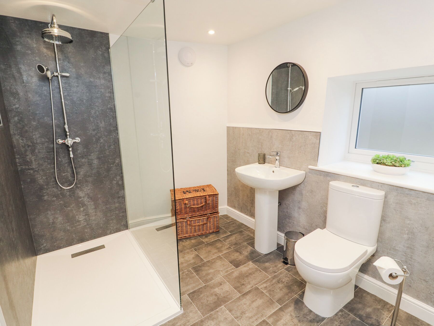 Un bagno moderno con doccia vetrata, lavabo bianco e servizi igienici.