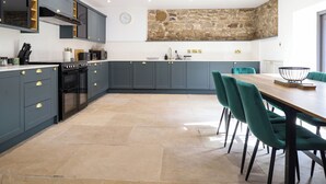 Una cucina moderna con mobili grigi, un'isola centrale e un'area pranzo con sedie color acquamarina.
