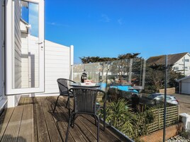 Un balcón con mesa y sillas, con vista a una piscina y jardín.
