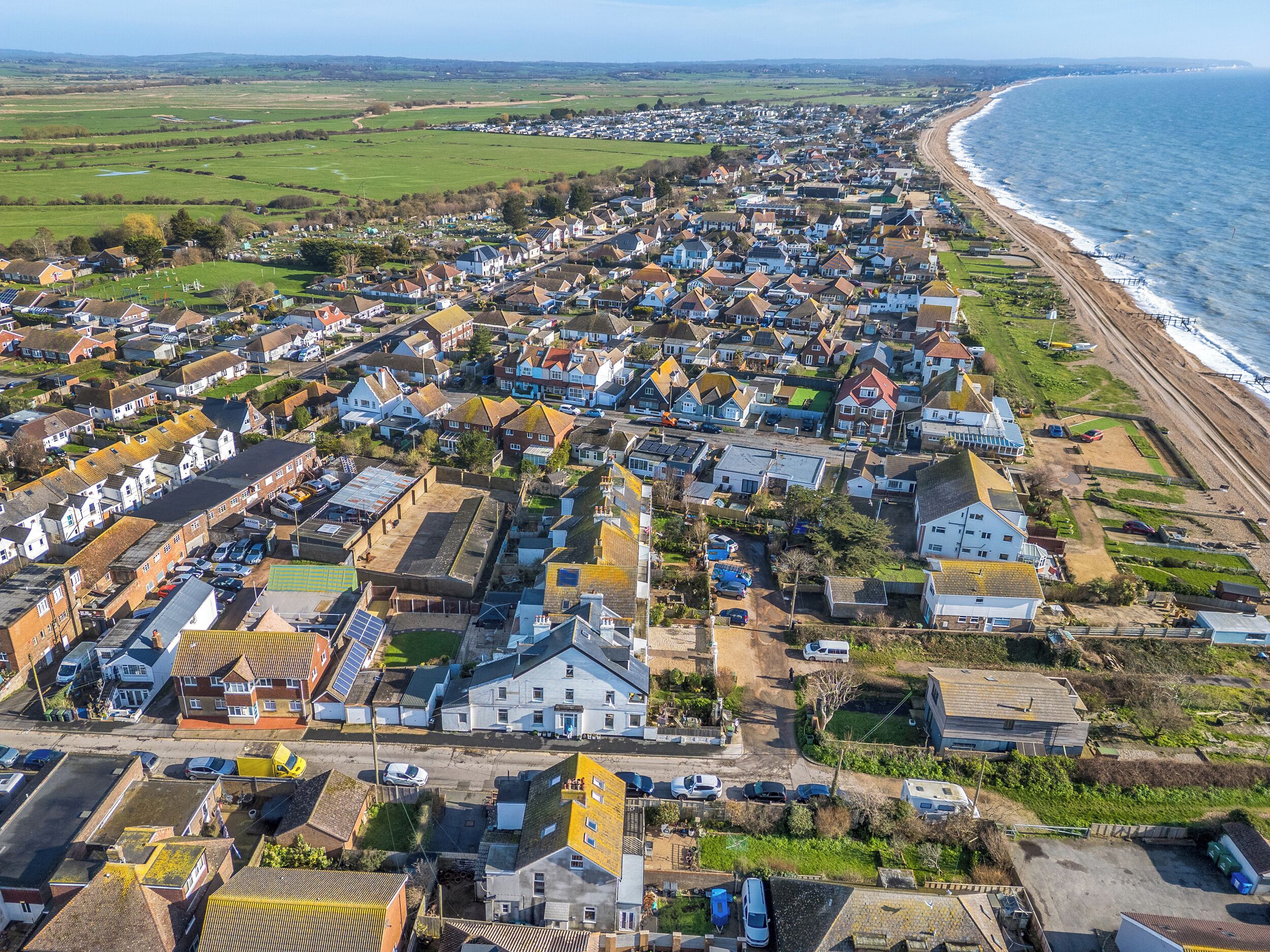 Vue aérienne d’une ville côtière, avec ses immeubles résidentiels, sa plage et un ciel dégagé.