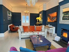 Een woonkamer met een bank, een salontafel, een open haard en een kroonluchter.