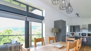 A modern kitchen with a view of the countryside, a dining area with wooden furniture, and a large window with a view. - 6 Strathtay Lodges (Aberfeldy)