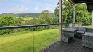 A covered outdoor seating area with wicker furniture and a view of a green landscape. - 6 Strathtay Lodges (Aberfeldy)