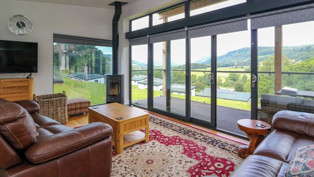 A spacious living room with leather sofas, a wooden coffee table, and a large TV. - 6 Strathtay Lodges (Aberfeldy)