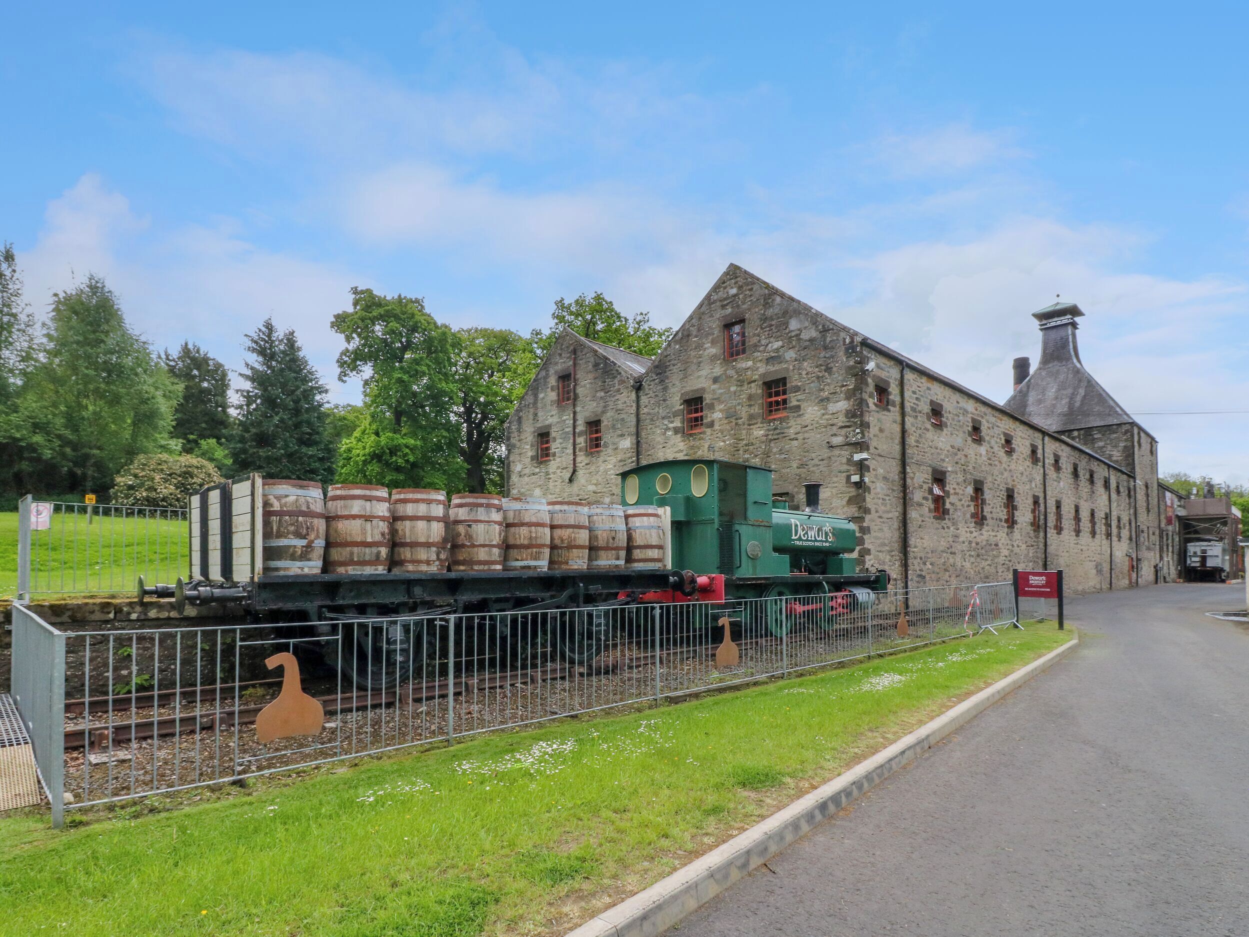 A historic building with a stone facade and a green train engine in front.