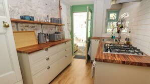 Een praktische keuken met een houten aanrecht, een gasfornuis en een klein spoelbakje.