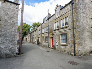 A narrow street lined with stone buildings, featuring traditional architecture with multiple windows and doors. - Top House (Buxton)