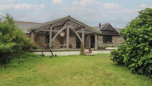 A rustic stone house with a wooden porch and a clock. - Horseshoe Cottage (Newquay)