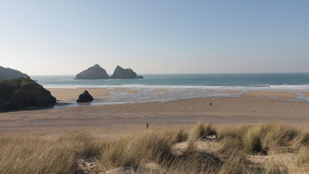A beach with sand dunes and two prominent rock formations in the distance. - Horseshoe Cottage (Newquay)